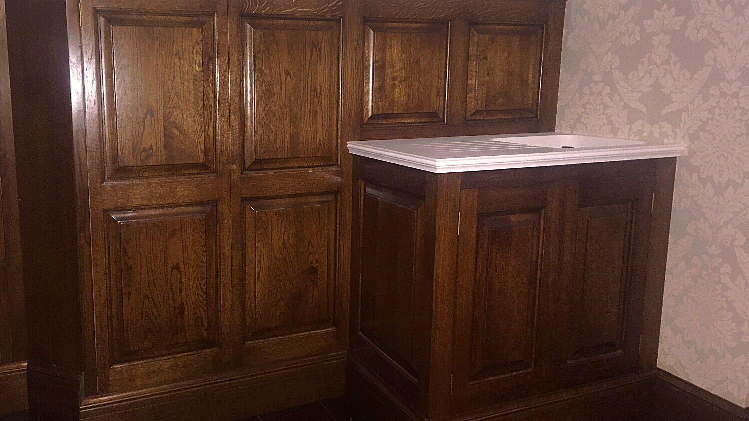 Oak panelling with a built-in cupboard and a pale stone top