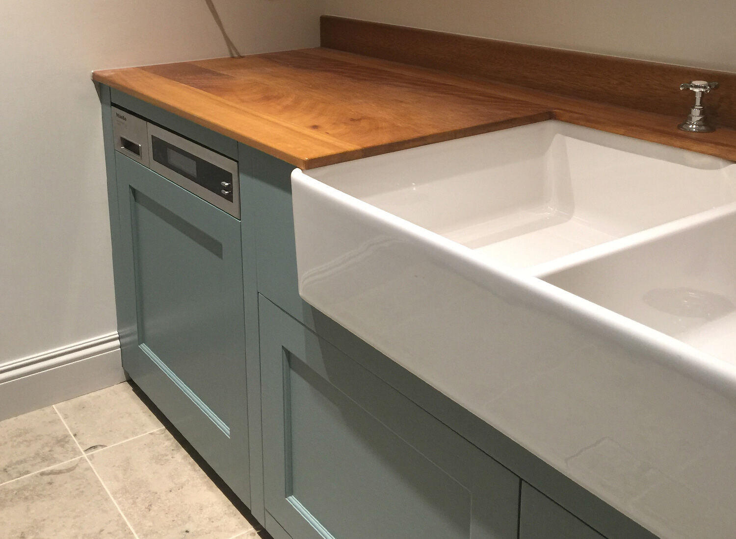 A painted utility run with a timber worktop and a double ceramic sink